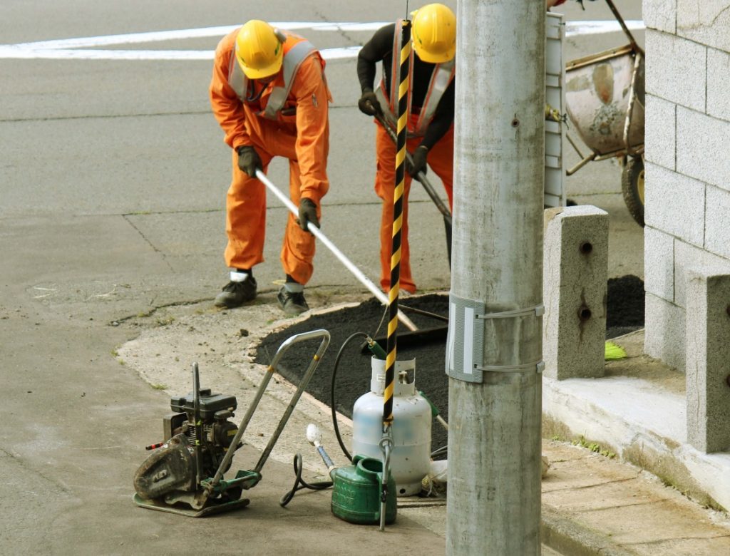 作業員がトンボで地面を均す写真