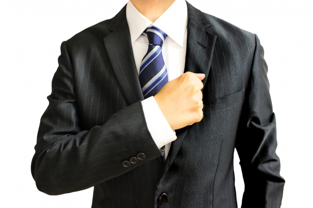 胸に拳を充てるスーツの男性