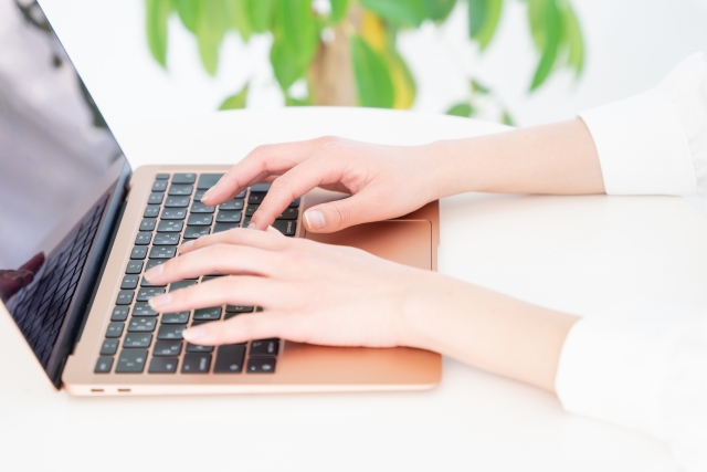 ゴールドピンクのmacbookを操作する女性