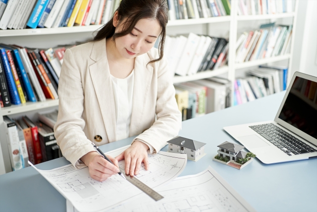 図面を書くオフィスカジュアルの女性
