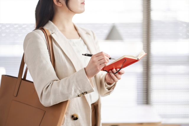 手帳にメモをとる女性社員